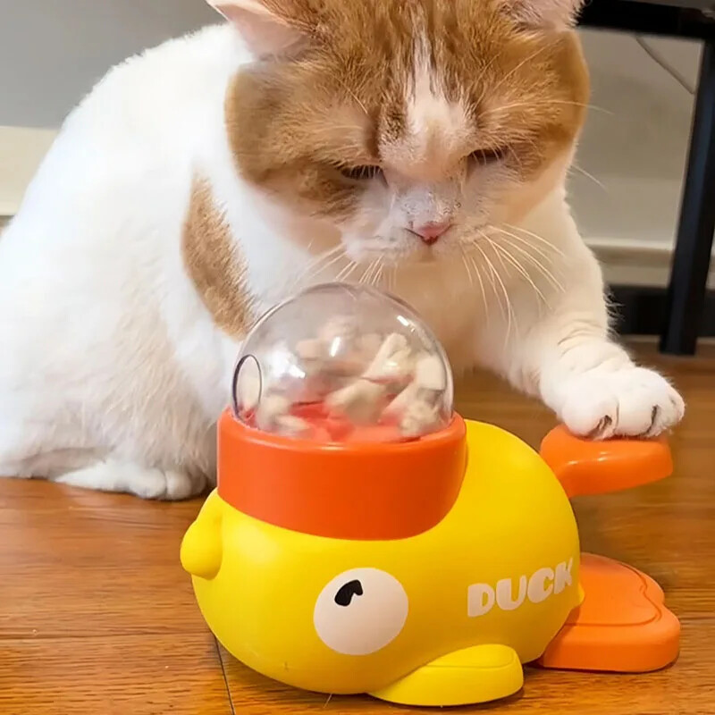 A cat pawing at the Duckpawl interactive duck treat dispenser